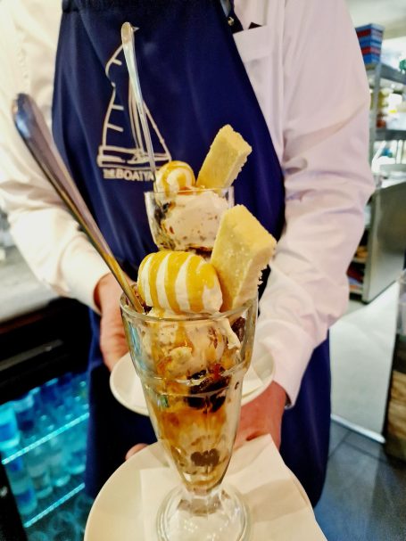 A dessert glass filled with ice cream, banana slices, and a swirl of cream.