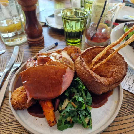 A plate of roast dinner with meat, vegetables, Yorkshire pudding, and gravy.