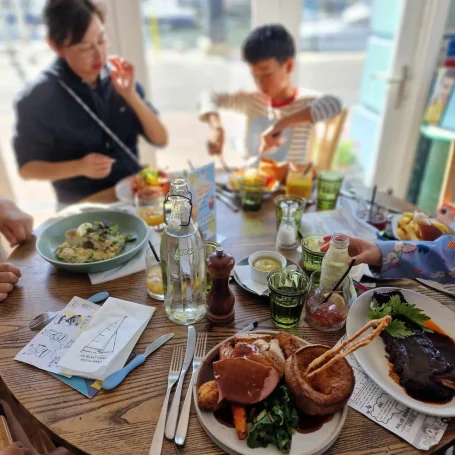 A family enjoying a meal with various dishes, drinks, and a lively atmosphere.