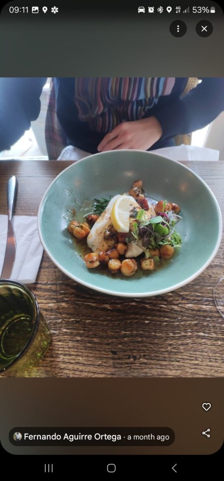 Plate with fillets of plaice with local queenie scallops with wedge of lemon and herb garnish